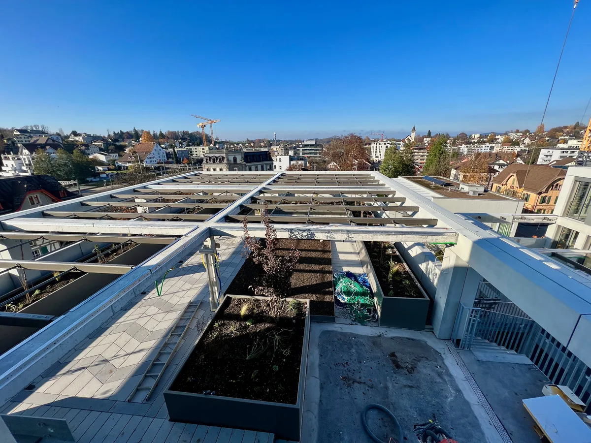 Man sieht eine grosse Terrasse von oben. Auf dieser sind mehrere Beete angelegt. Von der Terrasse hat man einen schönen Ausblick über Wetzikon.